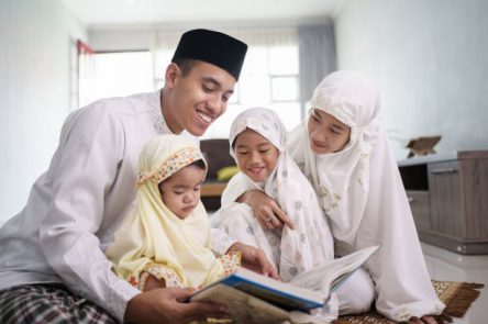 portrait of happy muslim family with children reading quran and pray together at home